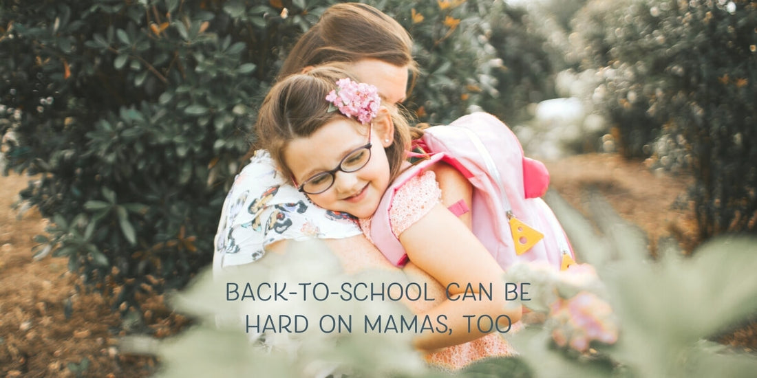 little girl with a pink backpack and glasses hugging her mom on the first day of school.