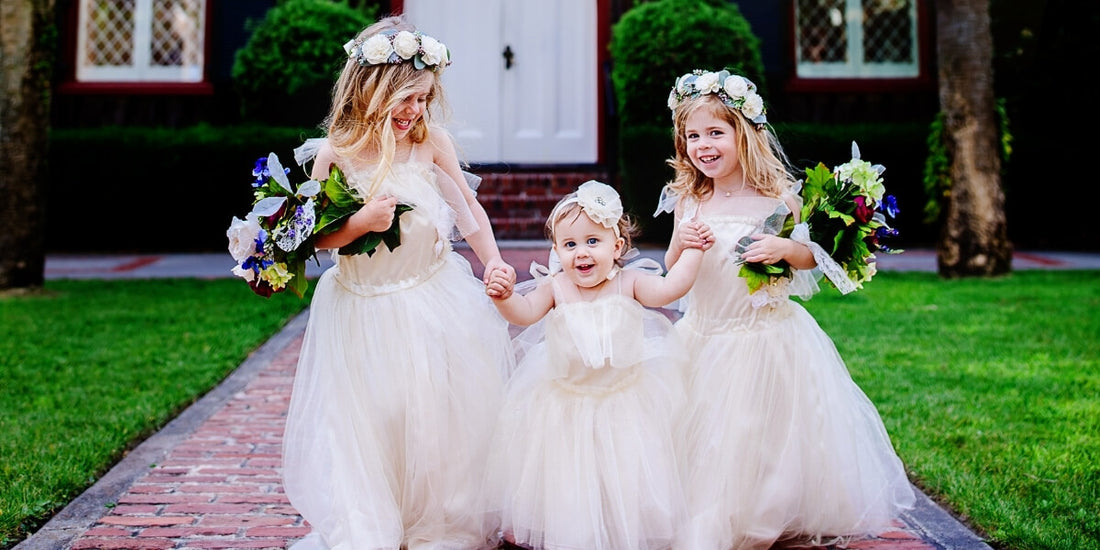 Three adorable flower girls wearing pearl jewelry and tulle dresses with flower crowns.