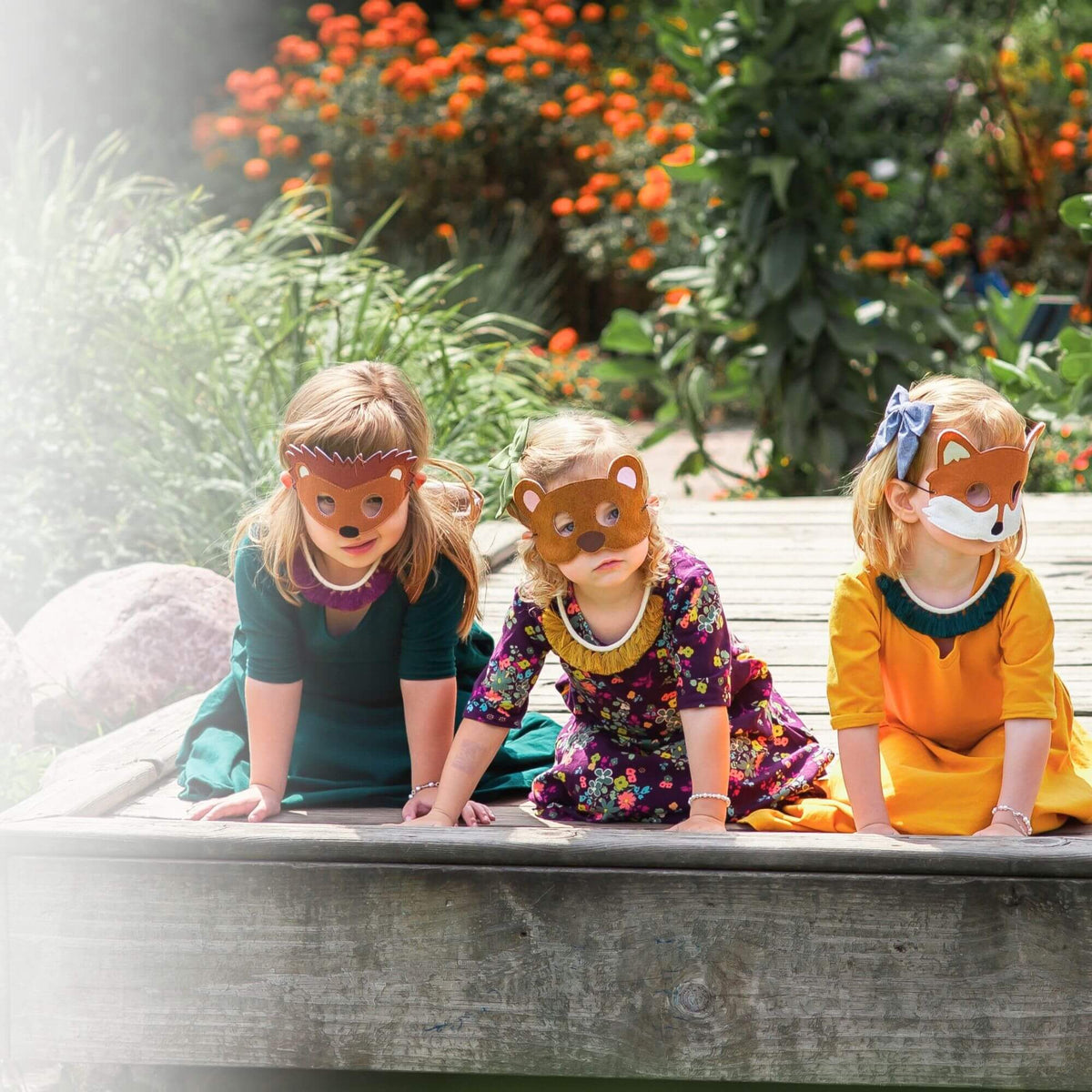 three little girls in costumes wearing pearl bracelets and animal masks.