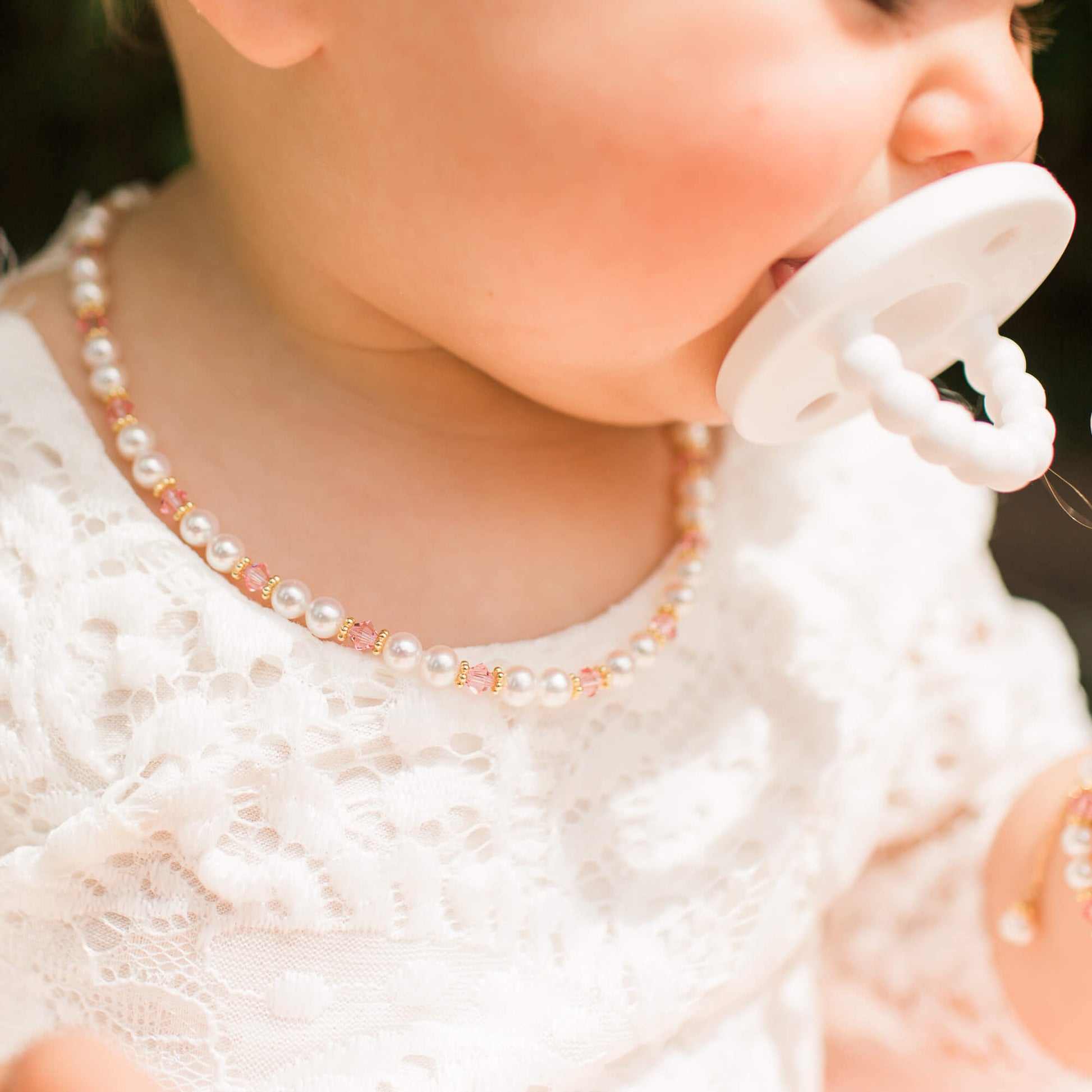 baby girl in a darling pearl and crystal necklace from little girl's pearls wearing a lace dress.